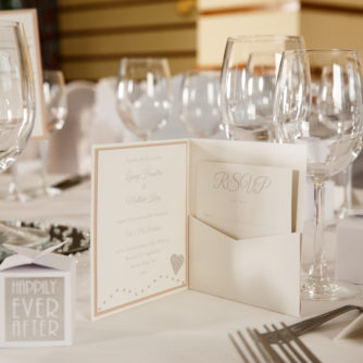 Close up of a wedding invitation in front of a place setting for a wedding at Mercure hotels
