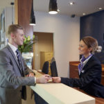 The reception desk at Mercure Sheffield Parkway Hotel, smiling receptionist hands man in suit his room key