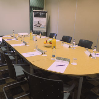 The Boardroom meeting room at Mercure Sheffield Parkway Hotel, flipboard, bottled water, stationery, bowl of fruit on table